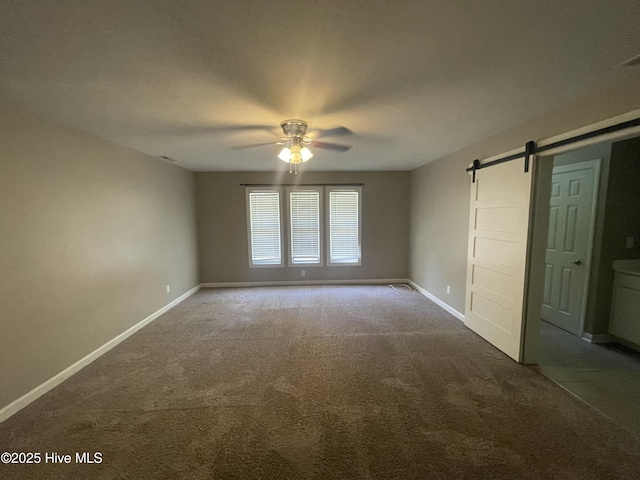 unfurnished bedroom featuring carpet flooring, a ceiling fan, baseboards, and a barn door