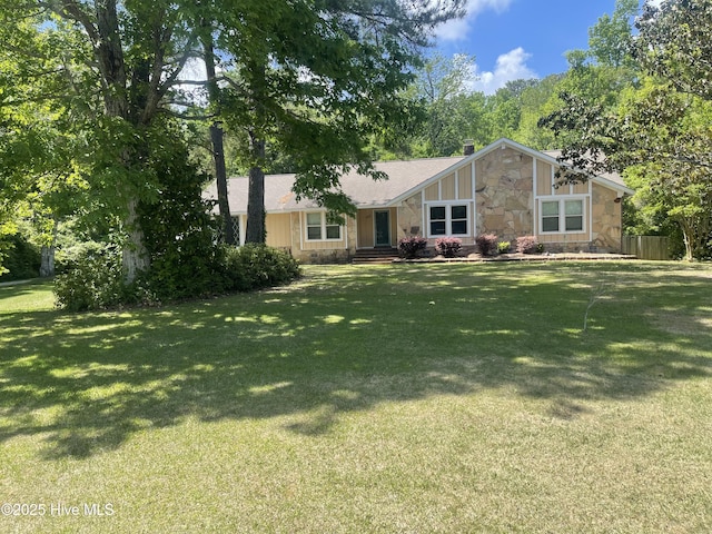 view of front of house featuring fence, a chimney, a front yard, and stone siding