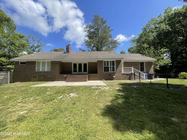 back of house with a chimney, a lawn, a patio area, brick siding, and fence