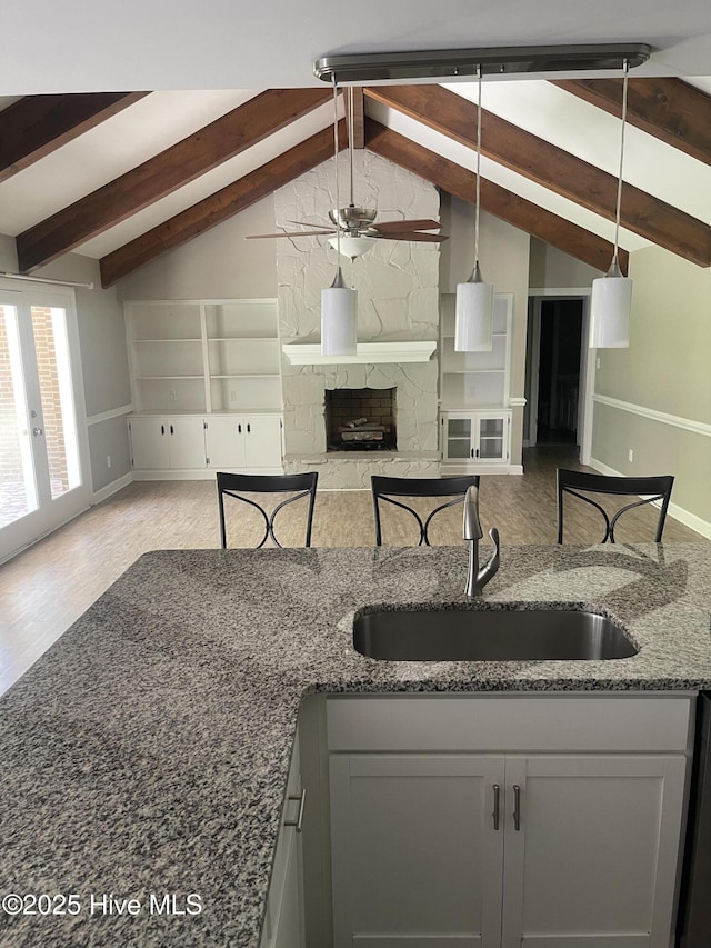 kitchen with a sink, vaulted ceiling with beams, and open floor plan