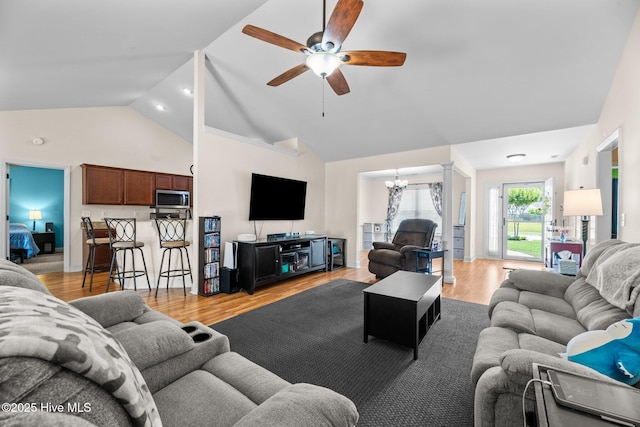 living room featuring high vaulted ceiling, ceiling fan with notable chandelier, and light wood-style floors