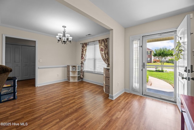 foyer entrance featuring an inviting chandelier, ornamental molding, baseboards, and wood finished floors