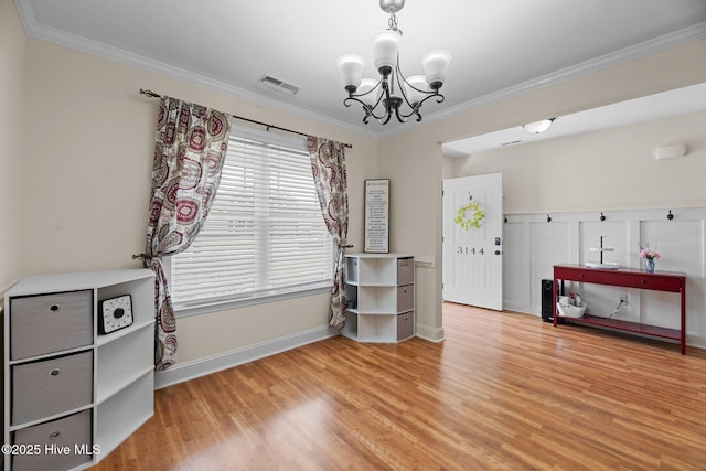 interior space featuring visible vents, crown molding, wood finished floors, baseboards, and a chandelier