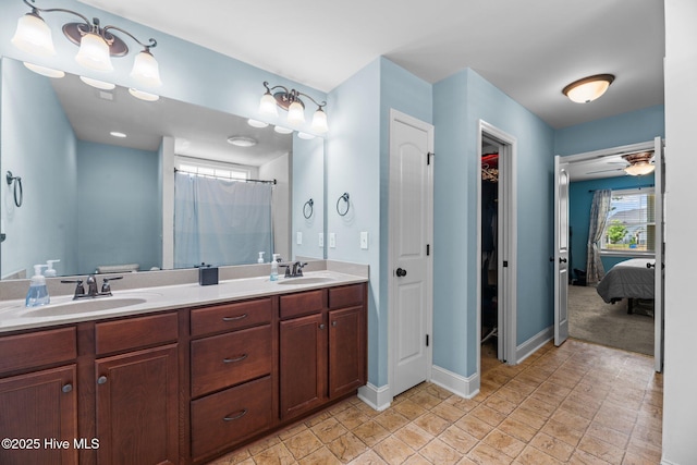 bathroom featuring double vanity, a sink, baseboards, and a ceiling fan