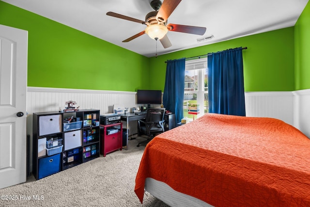 bedroom featuring carpet flooring, ceiling fan, visible vents, and a wainscoted wall