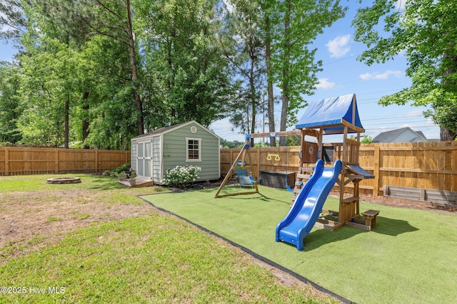 view of jungle gym featuring a lawn, an outdoor structure, a fenced backyard, and a shed