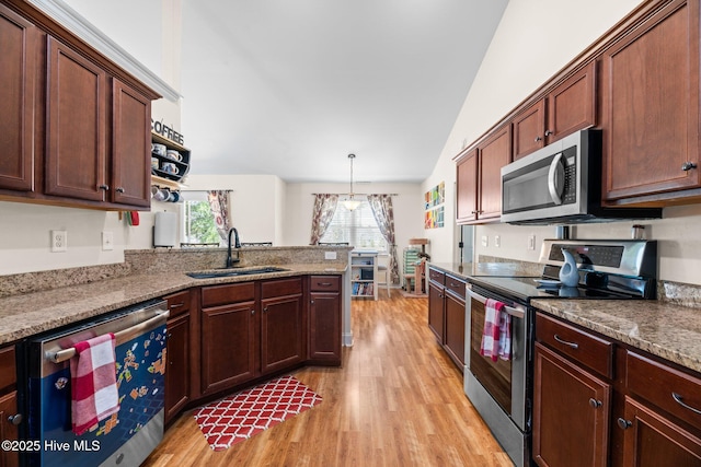 kitchen featuring light wood-type flooring, a sink, a peninsula, and stainless steel appliances