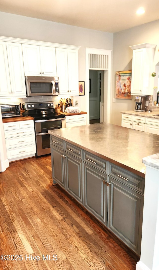 kitchen featuring appliances with stainless steel finishes, white cabinetry, gray cabinetry, wood finished floors, and light countertops