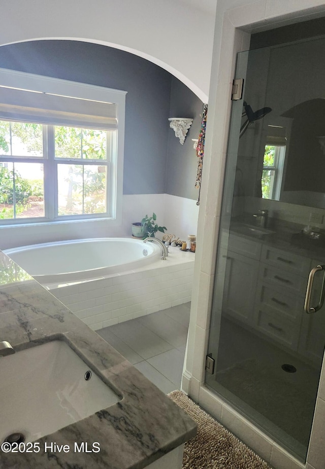 bathroom featuring a sink, healthy amount of natural light, a shower stall, and a bath