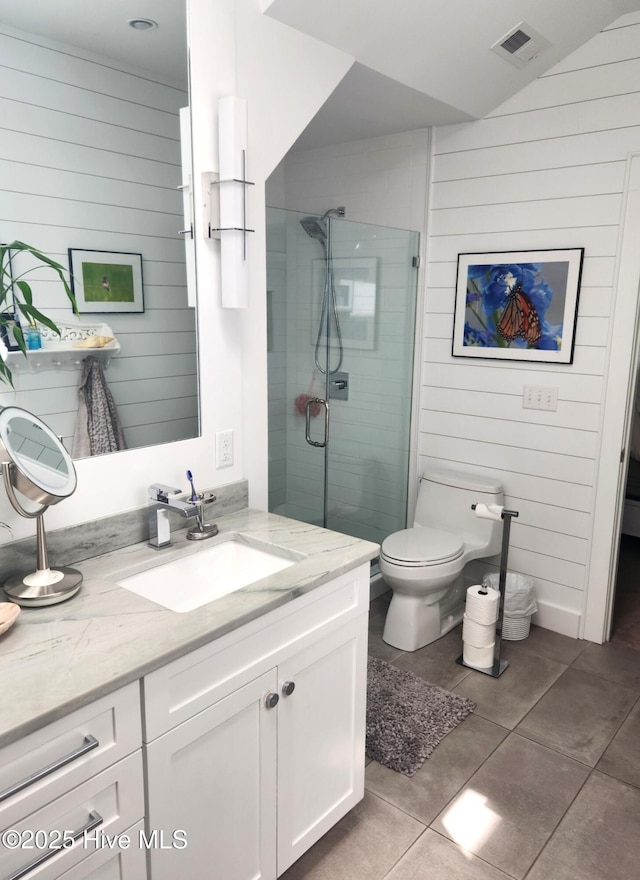 bathroom featuring a shower stall, tile patterned flooring, vanity, toilet, and wood walls