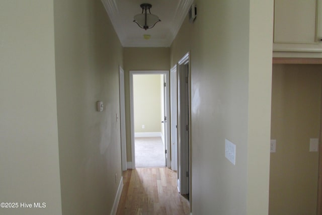 hall featuring crown molding, light wood-style flooring, baseboards, and visible vents