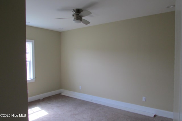 carpeted empty room featuring baseboards and a ceiling fan