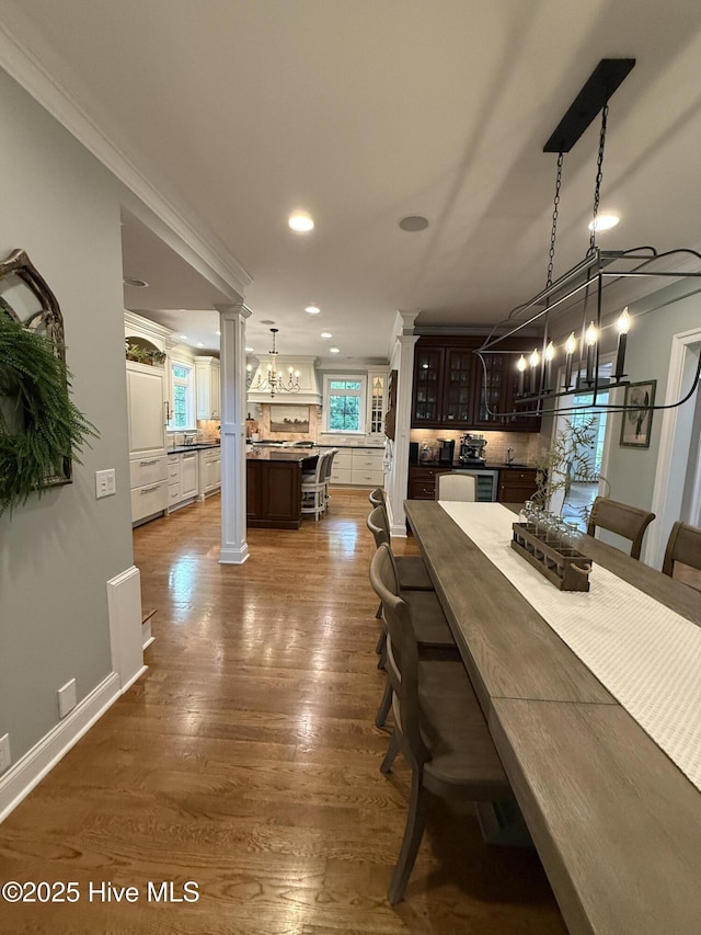 dining room with an inviting chandelier, decorative columns, and dark wood-style flooring