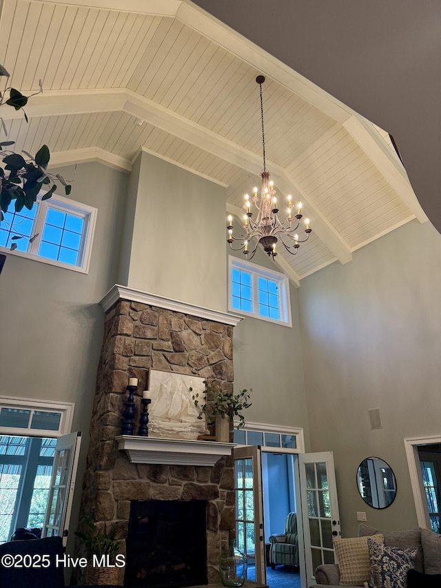 living room featuring a stone fireplace, wooden ceiling, high vaulted ceiling, beamed ceiling, and a chandelier