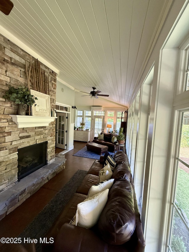 living area featuring ceiling fan, wooden ceiling, and a stone fireplace