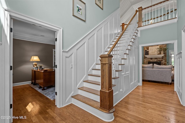 3681 Fairfield Way, Southport, NC 28461 - stairs with wood finished floors, a decorative wall, ornamental molding, a fireplace, and a high ceiling