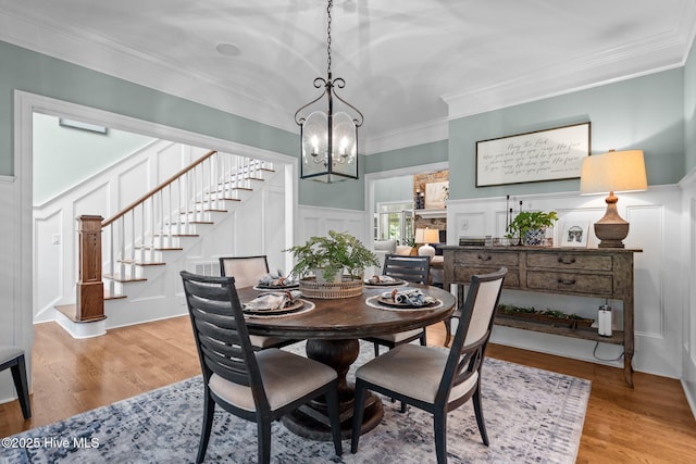 3681 Fairfield Way, Southport, NC 28461 - dining space with a decorative wall, stairway, a chandelier, ornamental molding, and light wood-style floors