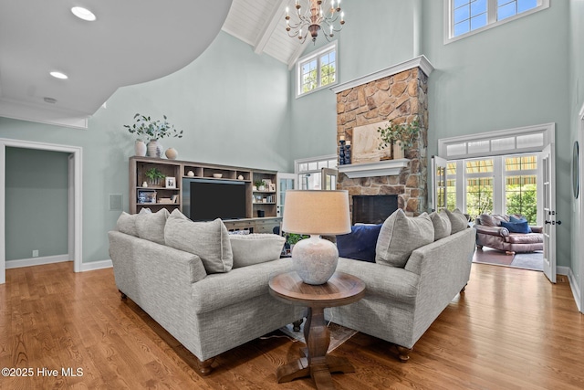 3681 Fairfield Way, Southport, NC 28461 - living room featuring high vaulted ceiling, a chandelier, wood finished floors, a stone fireplace, and recessed lighting