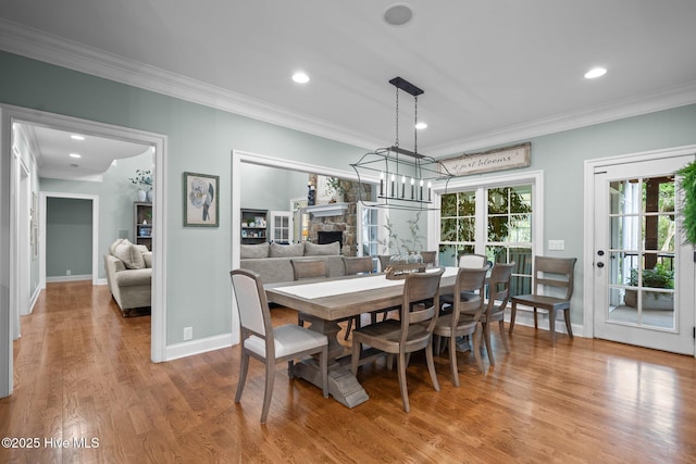 3681 Fairfield Way, Southport, NC 28461 - dining area featuring crown molding, wood finished floors, a stone fireplace, and recessed lighting
