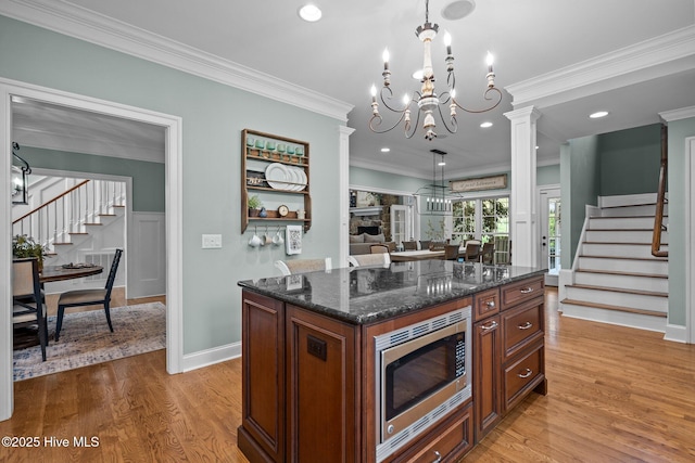 3681 Fairfield Way, Southport, NC 28461 - kitchen featuring stainless steel microwave, light wood-style floors, ornamental molding, dark stone counters, and a center island