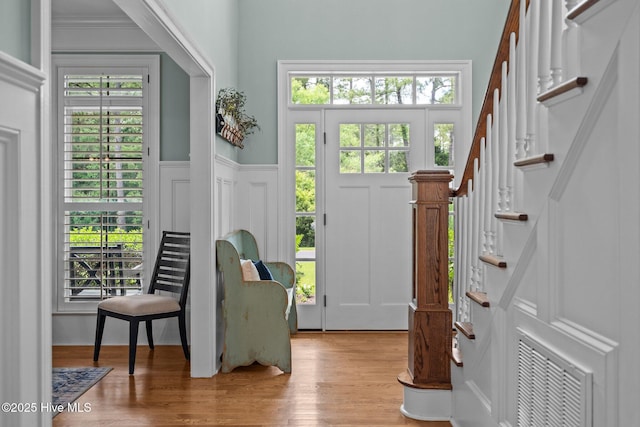 3681 Fairfield Way, Southport, NC 28461 - foyer entrance featuring a decorative wall, wood finished floors, a wainscoted wall, and stairs