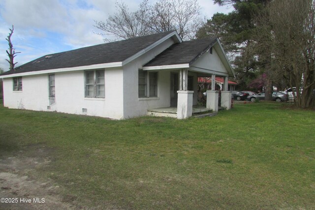 view of property exterior featuring a lawn, a shingled roof, stucco siding, and covered porch