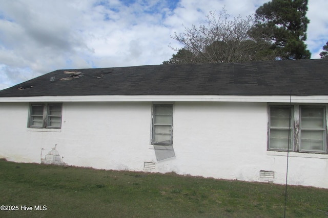 view of side of property featuring a shingled roof and stucco siding