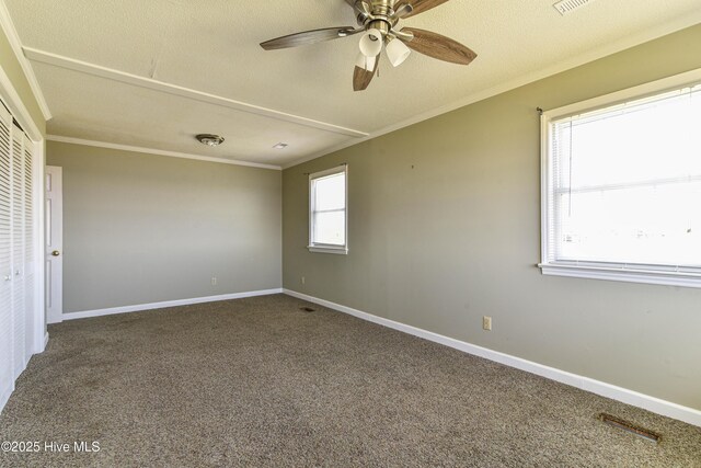 empty room featuring a textured ceiling, carpet, a ceiling fan, baseboards, and ornamental molding