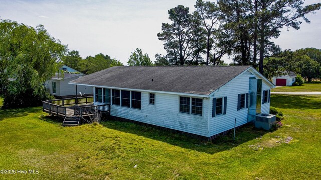 rear view of house with central air condition unit, a yard, a wooden deck, and a shingled roof