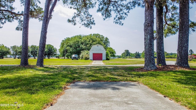 view of community featuring a yard, driveway, and a detached garage