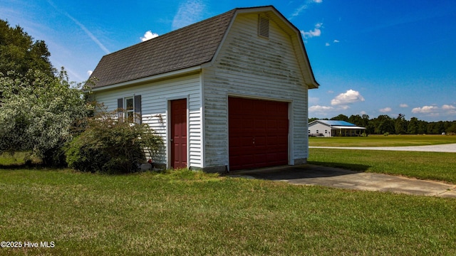 view of property exterior featuring an outdoor structure, driveway, roof with shingles, a yard, and a detached garage
