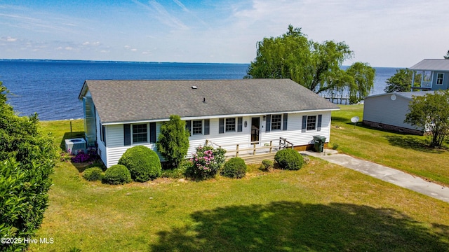 rear view of property with a lawn, a water view, cooling unit, and a shingled roof
