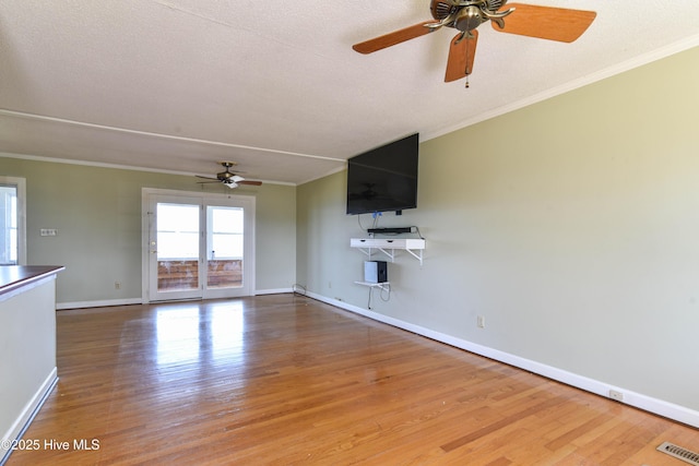 unfurnished living room featuring crown molding, a ceiling fan, visible vents, and wood finished floors