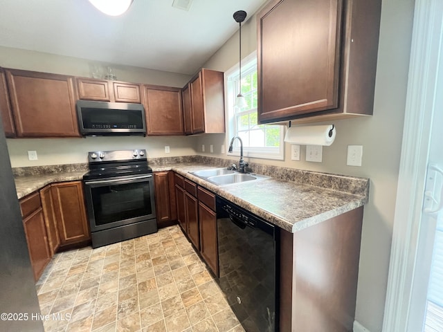 kitchen featuring a sink, pendant lighting, appliances with stainless steel finishes, and stone finish floor