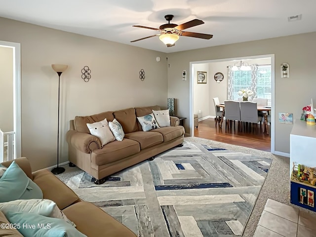 living area featuring visible vents, a ceiling fan, and baseboards