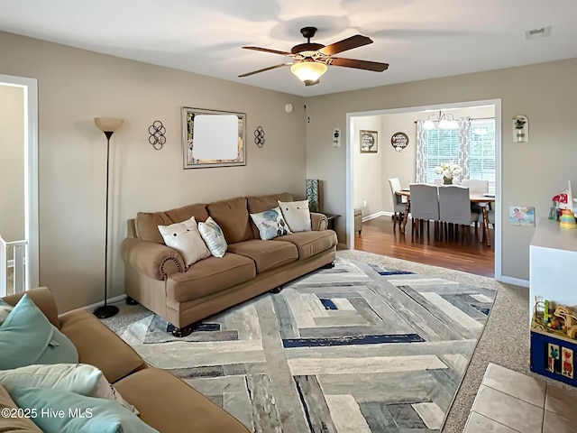 living room with visible vents, a ceiling fan, and baseboards
