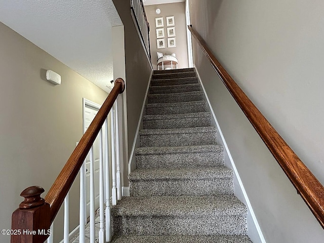 stairway with carpet and a textured ceiling