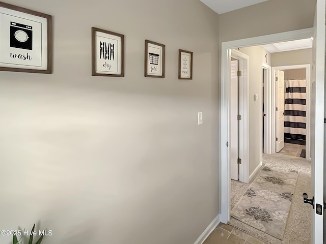 corridor featuring baseboards and tile patterned flooring