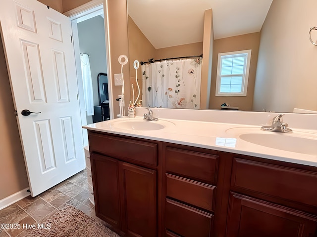 bathroom with double vanity, a sink, and baseboards