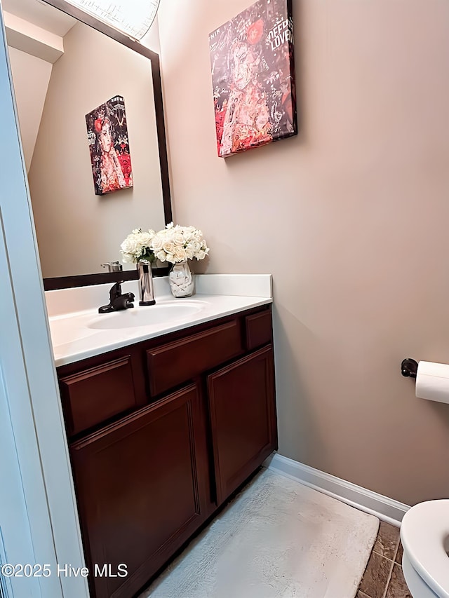 half bath featuring vanity, baseboards, and toilet