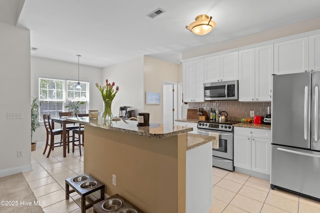 kitchen featuring appliances with stainless steel finishes, a kitchen island, light tile patterned flooring, and visible vents