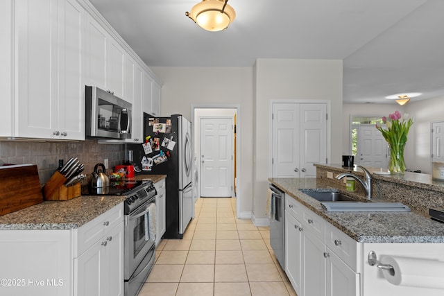 kitchen featuring light tile patterned flooring, white cabinetry, tasteful backsplash, a sink, and stainless steel appliances