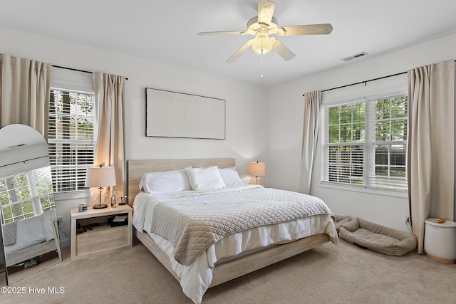 bedroom featuring ceiling fan, visible vents, multiple windows, and carpet