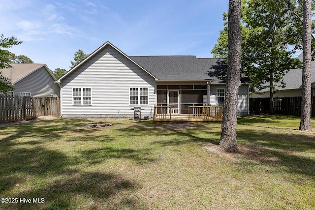 back of house featuring a lawn, a sunroom, a fenced backyard, and roof with shingles
