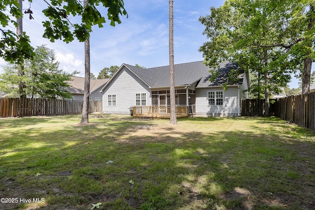 back of property featuring a shingled roof, a sunroom, a deck, a fenced backyard, and a yard