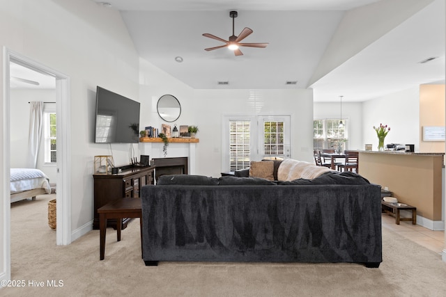 living area with ceiling fan, vaulted ceiling, and light carpet