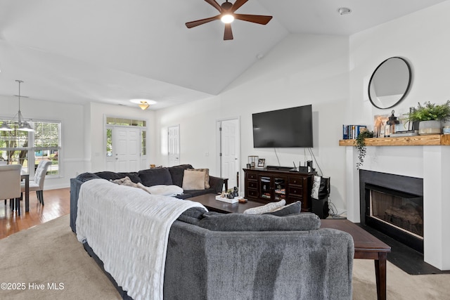 living area with a fireplace with flush hearth, vaulted ceiling, a ceiling fan, and wood finished floors