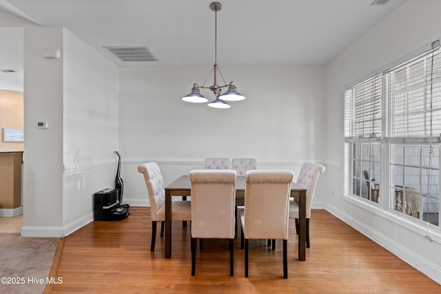 dining room with visible vents, baseboards, wood finished floors, and an inviting chandelier