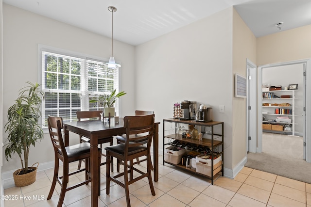 dining area with baseboards, light tile patterned flooring, and light carpet