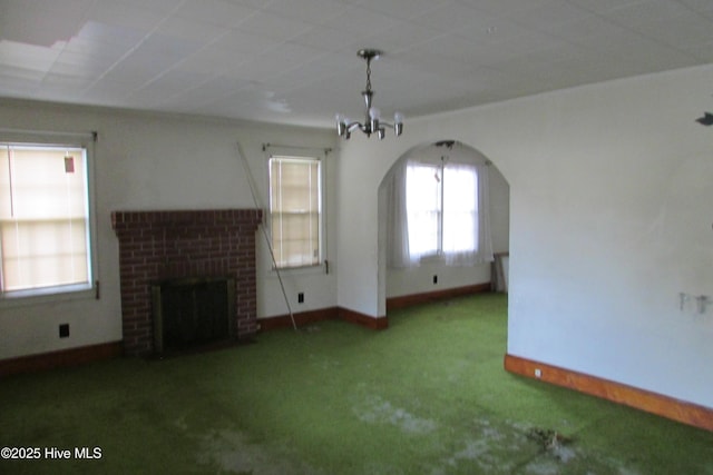 803 Mccoy St, Clinton, NC 28328 - unfurnished living room featuring a notable chandelier, a fireplace, carpet floors, arched walkways, and baseboards